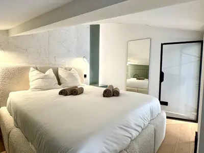 a bedroom with a large white bed with two towels on it at Duplex design - Old Town 50 m from the sea in Villefranche-sur-Mer
