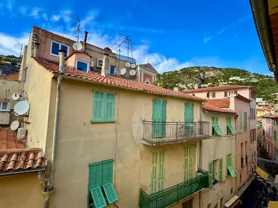a group of buildings with green shutters and a mountain at Duplex design - Old Town 50 m from the sea in Villefranche-sur-Mer