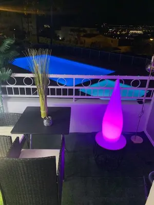a table with a pink lamp on a balcony at night at Studio 27m2 en résidence standing piscine in Nice