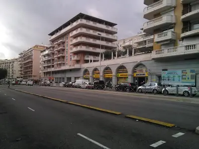 an empty street with cars parked in front of a building at Californie Appartement in Nice