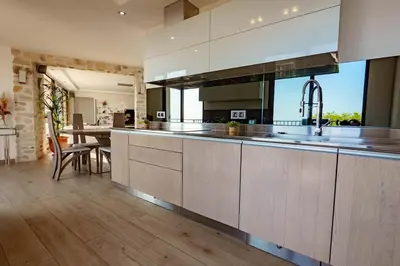 a kitchen with white cabinets and a dining room at Appartment - Panoramic Sea View - Swimming Pool in Villefranche-sur-Mer