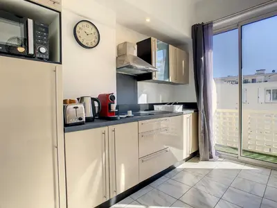 a kitchen with white cabinets and a clock on the wall at Nestor&Jeeves - CITRONNIER AZUR - Central - Close sea in Nice