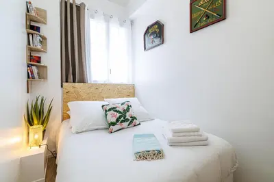 a bedroom with a bed with white sheets and a window at Centre Nice - 10 min plage - 5 min des transports en commun in Nice