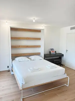 a bedroom with a large white bed with a wooden headboard at Seaside Azur in Saint-Laurent-du-Var