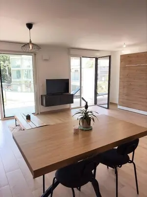 a large wooden table in a living room with a tv at Seaside Azur in Saint-Laurent-du-Var