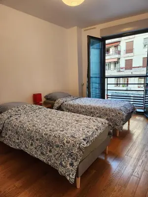 two beds in a room with a large window at Charmant 2 pièces, centre ville & proche gare in Nice
