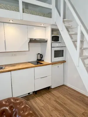 a kitchen with white cabinets and a staircase at Appartement central in Nice