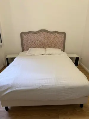 a bed with white sheets and a wooden headboard at Deux pièces Libération - Balcon in Nice