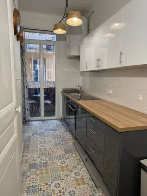 a kitchen with a counter and a tile floor at Deux pièces Libération - Balcon in Nice