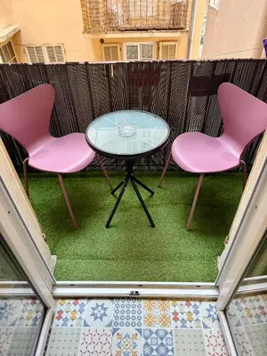 two pink chairs and a glass table on a balcony at Deux pièces Libération - Balcon in Nice