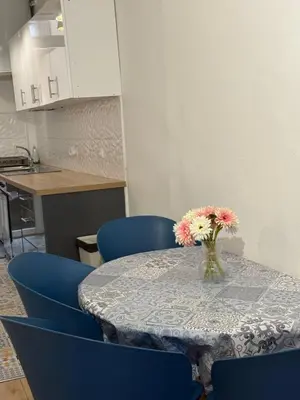 a table with blue chairs and a vase of flowers on it at Deux pièces Libération - Balcon in Nice