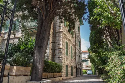 a brick building with a tree next to a street at Appartement Original cœur de ville -AC- in Nice