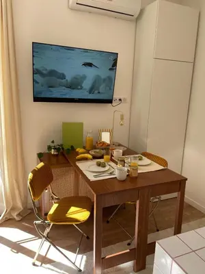 a dining room table with two chairs and a television on the wall at Under the Citrus Trees in Nice