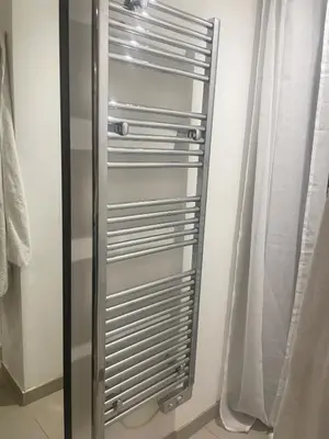 a metal radiator in a bathroom next to a curtain at Appartment with private garden in city center Nice in Nice