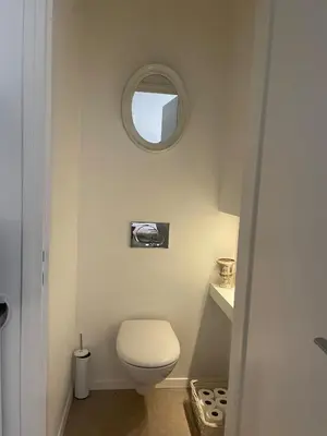 a bathroom with a toilet and a round mirror at Appartment with private garden in city center Nice in Nice