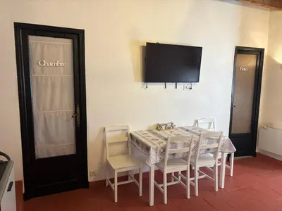 a dining room with a table and chairs and a television at Morning Coffee & Cobblestones - A True French Village Stay in Villefranche-sur-Mer
