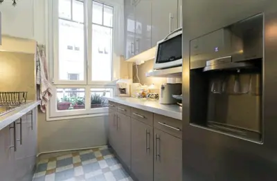 a kitchen with white cabinets and a large window at Chambre chez l'habitant - Centre Nice 10 min de la plage in Nice