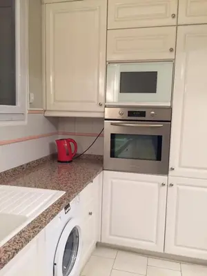 a kitchen with white cabinets and a washer and dryer at 115 Promenade des Anglais in Nice