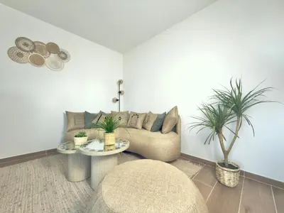 a living room with a couch and two potted plants at L'Elydris - Piscine Wifi Rooftop in Saint-Laurent-du-Var