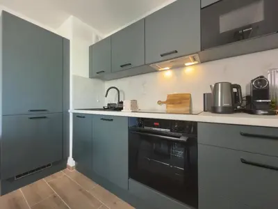 a kitchen with gray cabinets and a black oven at L'Elydris - Piscine Wifi Rooftop in Saint-Laurent-du-Var