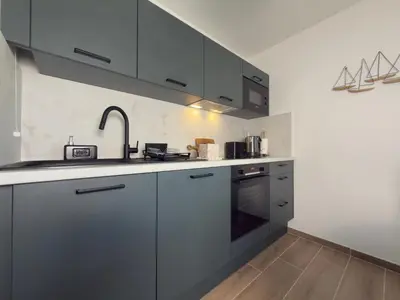 a kitchen with gray cabinets and a sink at L'Elydris - Piscine Wifi Rooftop in Saint-Laurent-du-Var