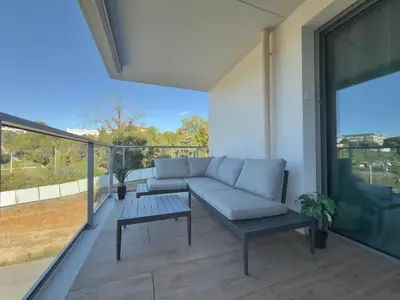 a living room with a couch and a table on a balcony at L'Elydris - Piscine Wifi Rooftop in Saint-Laurent-du-Var