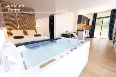 a room with a bath tub with a bed in the background at Romantic suite with jacuzzi in La Trinité