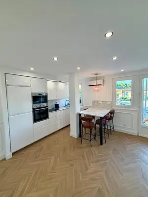 a kitchen with white cabinets and a table and chairs at Appartement avec jardin - Front de mer St Laurent-du-Var in Saint-Laurent-du-Var