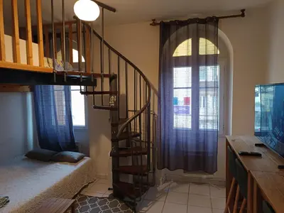 a living room with a spiral staircase next to a window at Studio in Nice