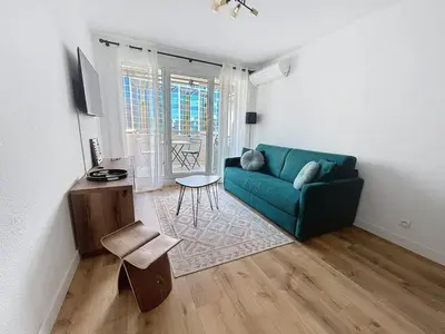 a living room with a blue couch and a table at Sunny studio on a high floor with terrace in Nice