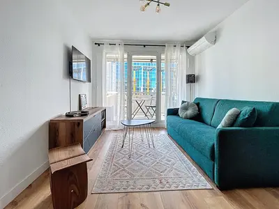 a living room with a blue couch and a table at Sunny studio on a high floor with terrace in Nice