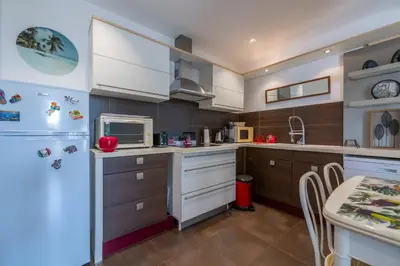 a kitchen with a white refrigerator and a table at louna in Beaulieu-sur-Mer