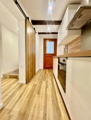 an empty kitchen with wooden floors and a red door at Jolie studio - 2 personnes - Saint laurent du Var in Saint-Laurent-du-Var