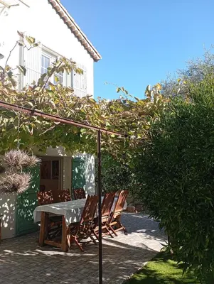 a patio with a table and chairs under an umbrella at Bas de villa , coin détente extérieur et parking in Cagnes-sur-Mer