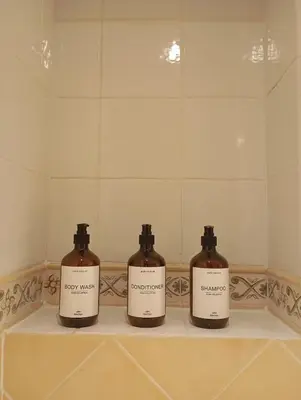 three bottles of soap sitting on a shelf in a bathroom at Bas de villa , coin détente extérieur et parking in Cagnes-sur-Mer