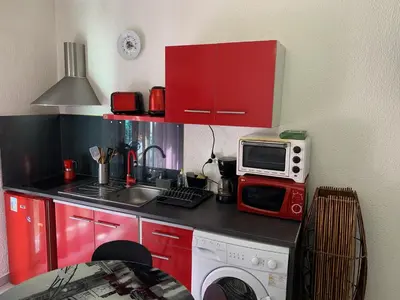 a small kitchen with red cabinets and a microwave at Studio NICE near the sea in Nice