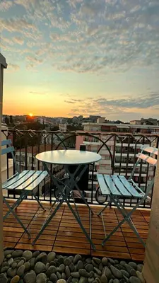 a table and two chairs on a balcony with the sunset at Beachfront Appartment Nice Promenade des anglais 2 terraces in Nice