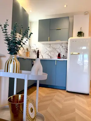 a kitchen with blue cabinets and a white refrigerator at Beachfront Appartment Nice Promenade des anglais 2 terraces in Nice
