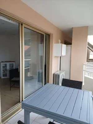 a blue table in a living room with a sliding glass door at vacances au soleil in Cagnes-sur-Mer