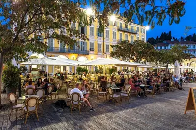 a group of people sitting in chairs at tables in front of a building at Plein centre, calme et cosy in Nice