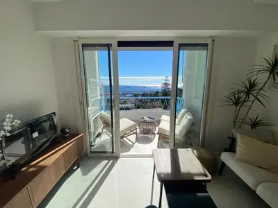 a living room with a couch and a tv and a balcony at mure in Beaulieu-sur-Mer