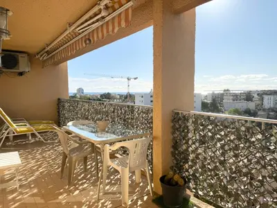 a patio with a table and chairs on a balcony at 2 pièces cosy avec grande terrasse & piscine in Cagnes-sur-Mer