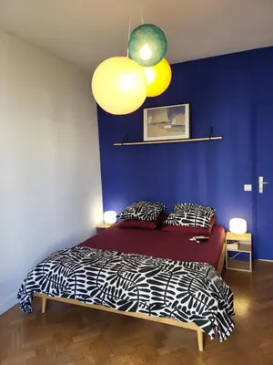 a bedroom with a bed and a blue wall at 2P cosy avec terrasse, vue mer & plages à pied in Nice
