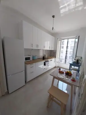 a kitchen with white cabinets and a table in it at Spacious apartment with balcony - Nice center in Nice