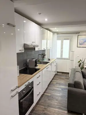 a kitchen with white cabinets and a couch at T2 cosy et climatise Vieux Nice Garibaldi in Nice