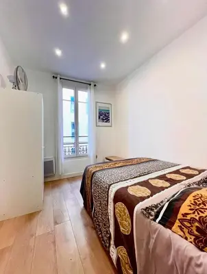 a bedroom with a bed and a large window at Beaumont Résidence in Nice