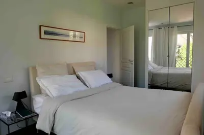 a bedroom with a large white bed and a mirror at Luxury villa with Pool and Garden perfect location in Beaulieu-sur-Mer
