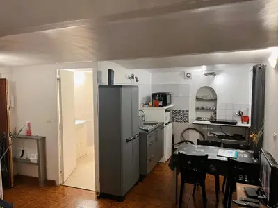 a kitchen with a refrigerator and a table in it at appartement entresol nice 1,2 kilomètre de la plage mer promenade in Nice