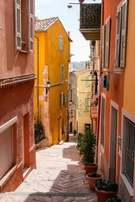 an alley with buildings and potted plants on a street at Charmant studio rénové – Place de la République in Villefranche-sur-Mer