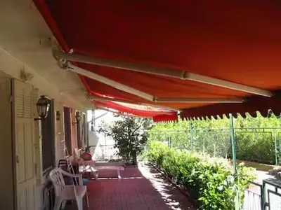 a patio with a red umbrella and a table and chairs at 1 chambre chez l'habitant, vue mer, ville et plage in Nice